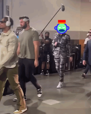 A Man Wearing Headphones And A Suit Has A Green Monkey On His Head GIF