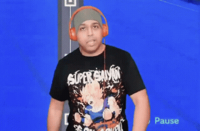A Man Wearing Headphones And A Super Saiyan T-Shirt Is Standing In Front Of A Blue Screen . GIF