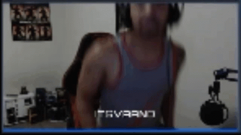 A Man Wearing Headphones And A Tank Top Is Standing In Front Of A Microphone .. GIF