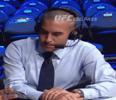 A Man Wearing Headphones And A Tie Is Sitting At A Table With His Hands Folded . GIF