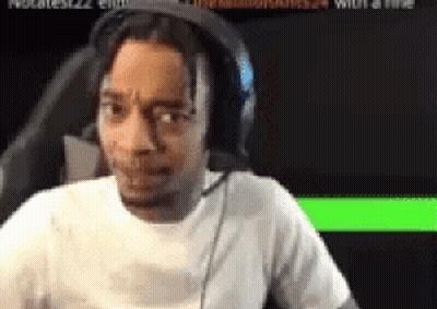 A Man Wearing Headphones And A White Shirt Is Sitting In Front Of A Computer Screen . GIF
