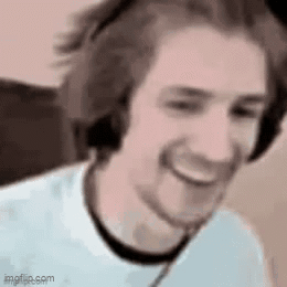 A Man Wearing Headphones And A White Shirt Is Smiling And Looking At The Camera . GIF