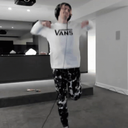 A Man Wearing Headphones And A White Vans Sweatshirt Is Dancing GIF