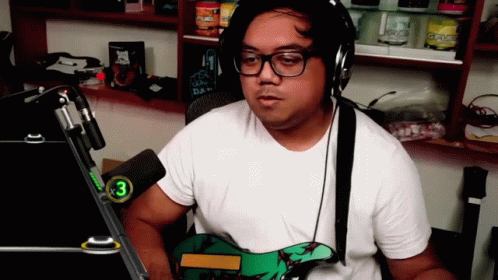 A Man Wearing Headphones And Glasses Is Playing A Guitar GIF