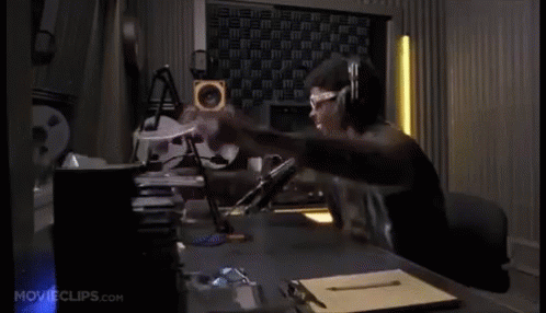 A Man Wearing Headphones And Glasses Is Sitting At A Desk In A Room With Movieclips.com On The Bottom Of The Screen GIF