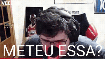 A Man Wearing Headphones And Glasses Is Sitting In Front Of A Bulls Poster .. GIF