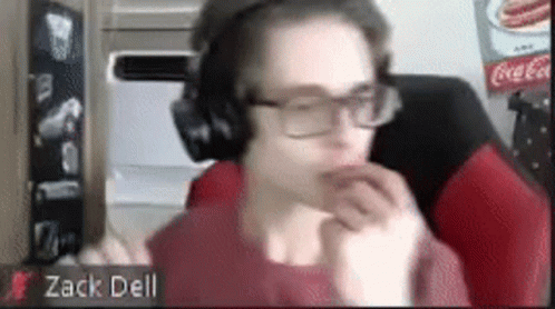 A Man Wearing Headphones And Glasses Is Sitting In Front Of A Coca Cola Sign . GIF