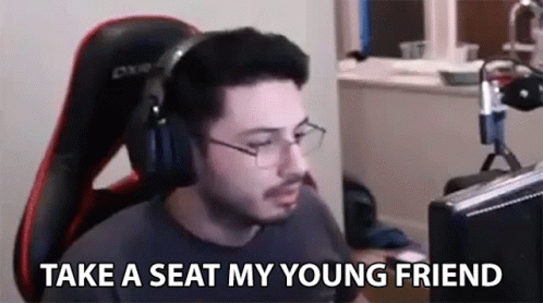 A Man Wearing Headphones And Glasses Is Sitting In Front Of A Computer And Talking To His Young Friend . GIF