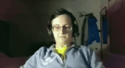 A Man Wearing Headphones And Glasses Is Sitting In Front Of A Computer Monitor . GIF