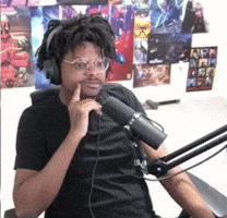 A Man Wearing Headphones And Glasses Is Sitting In Front Of A Microphone .. GIF