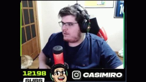 A Man Wearing Headphones And Glasses Is Sitting In Front Of A Microphone With The Number 12198 In The Corner GIF