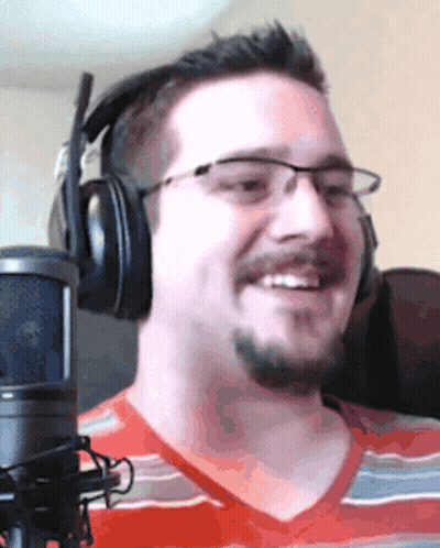 A Man Wearing Headphones And Glasses Is Smiling GIF