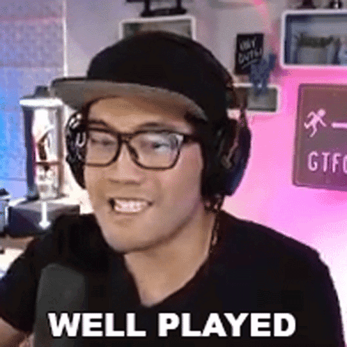 A Man Wearing Headphones And Glasses Is Talking Into A Microphone And Saying Well Played . GIF