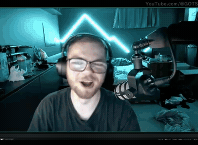 A Man Wearing Headphones And Glasses Stands In Front Of A Microphone With Youtube.com In The Corner GIF