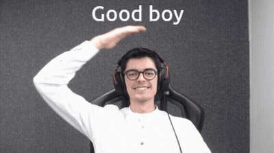 A Man Wearing Headphones And Glasses Stands In Front Of A Wall That Says Good Boy GIF