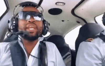 A Man Wearing Headphones And Goggles Is Flying A Small Plane . GIF