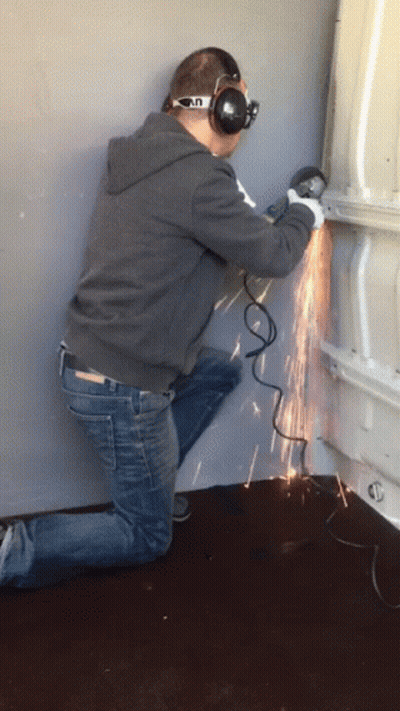 A Man Wearing Headphones And Goggles Is Using A Grinder To Cut A Piece Of Metal GIF