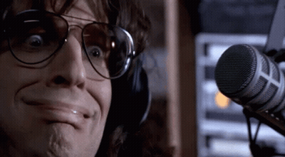 A Man Wearing Headphones And Sunglasses Is Making A Funny Face In Front Of A Microphone . GIF