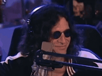 A Man Wearing Headphones And Sunglasses Is Smiling In Front Of A Microphone . GIF
