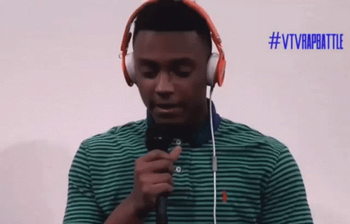 A Man Wearing Headphones Holds A Microphone In Front Of A #Vtvrapbattle Sign GIF