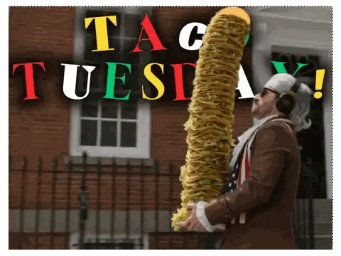 A Man Wearing Headphones Holds A Very Long Taco In Front Of A Sign That Says " Taco Tuesday " Sticker