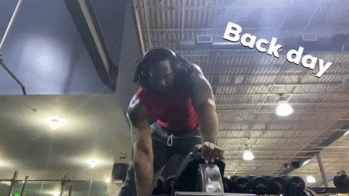 A Man Wearing Headphones In A Gym With The Words Back Day Written On The Ceiling GIF
