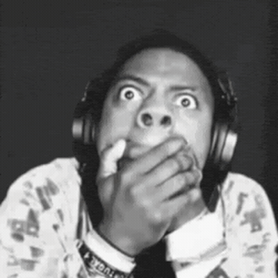 A Man Wearing Headphones Is Covering His Mouth With His Hand And Making A Funny Face . GIF