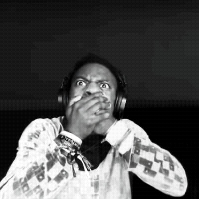 A Man Wearing Headphones Is Covering His Mouth With His Hands . GIF