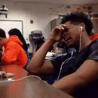 A Man Wearing Headphones Is Crying While Sitting At A Desk GIF