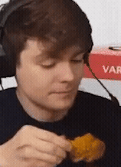 A Man Wearing Headphones Is Eating Chicken Nuggets . GIF