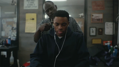 A Man Wearing Headphones Is Getting His Hair Cut By A Man Wearing A Striped Shirt GIF