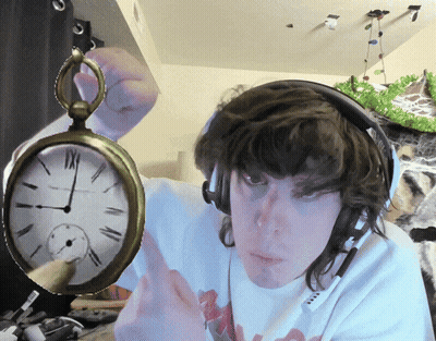 A Man Wearing Headphones Is Holding A Pocket Watch With Roman Numerals Including Xii On It GIF