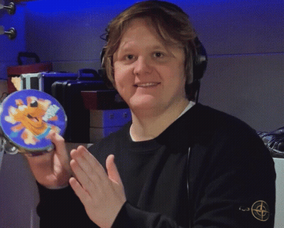 A Man Wearing Headphones Is Holding A Tambourine With A Picture Of A Cartoon Character On It GIF