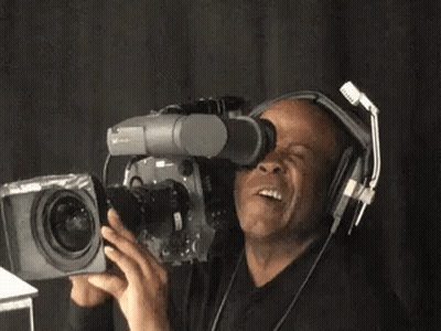 A Man Wearing Headphones Is Holding A Video Camera GIF