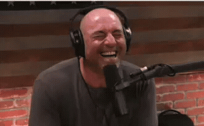A Man Wearing Headphones Is Laughing While Sitting In Front Of A Microphone . GIF