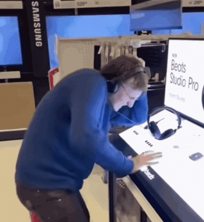 A Man Wearing Headphones Is Looking At A Display For Beats Studio Pro GIF