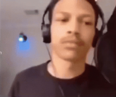 A Man Wearing Headphones Is Looking At The Camera And Making A Funny Face . GIF