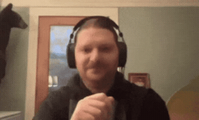 A Man Wearing Headphones Is Making A Fist In Front Of A Bear . GIF
