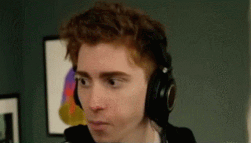 A Man Wearing Headphones Is Making A Funny Face And Looking At The Camera . GIF