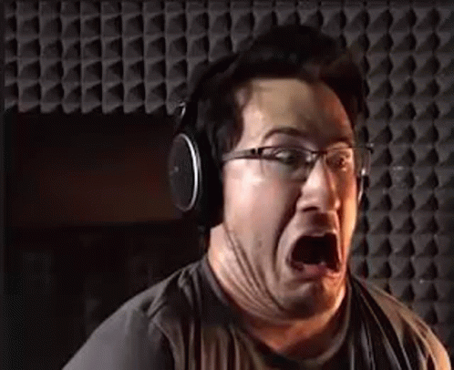 A Man Wearing Headphones Is Making A Funny Face In A Recording Studio . GIF