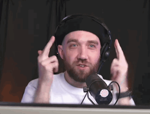 A Man Wearing Headphones Is Making A Funny Face In Front Of A Microphone GIF