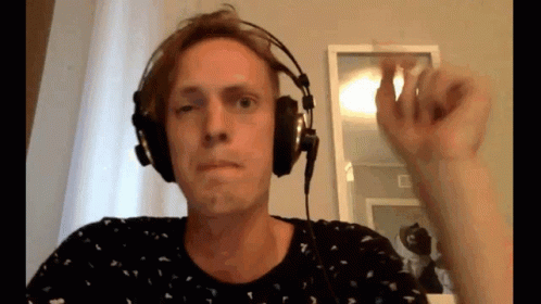 A Man Wearing Headphones Is Making A Funny Face In Front Of A Mirror . GIF
