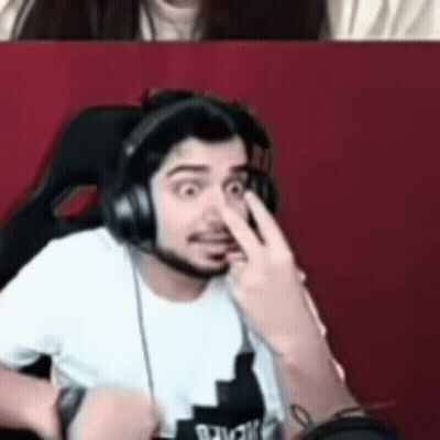 A Man Wearing Headphones Is Making A Funny Face While A Woman Looks On . GIF