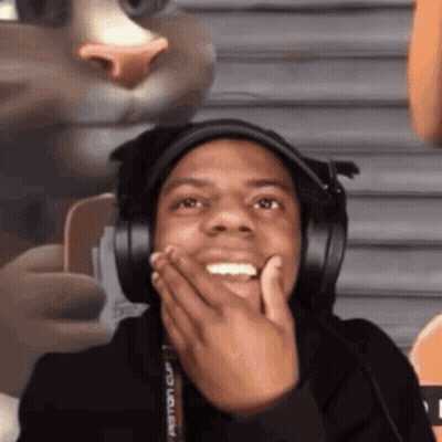 A Man Wearing Headphones Is Making A Funny Face While Holding His Hand To His Face . GIF