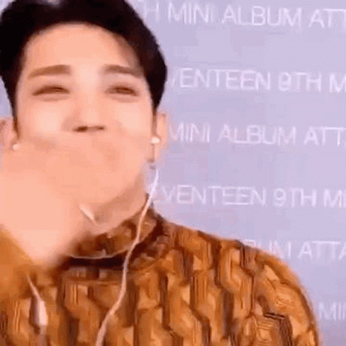 A Man Wearing Headphones Is Making A Funny Face While Holding His Hand To His Mouth . GIF