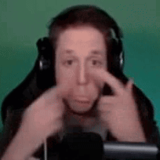 A Man Wearing Headphones Is Making A Funny Face While Sitting In Front Of A Microphone . GIF