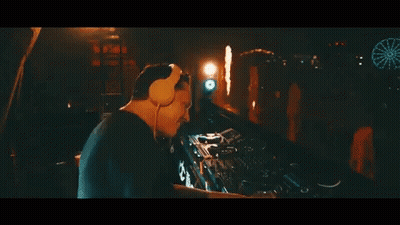 A Man Wearing Headphones Is Playing A Dj Set At A Party GIF