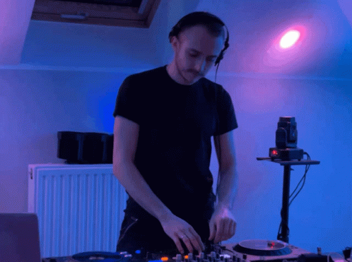 A Man Wearing Headphones Is Playing A Record On A Turntable GIF