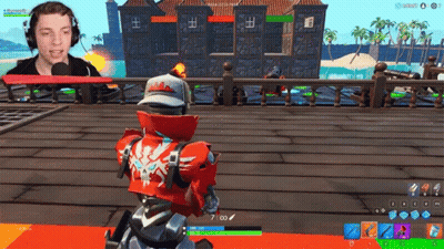 A Man Wearing Headphones Is Playing A Video Game With A Robot In The Background GIF