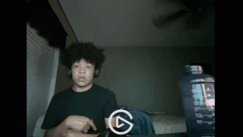 A Man Wearing Headphones Is Playing A Video With A Play Button In The Corner GIF